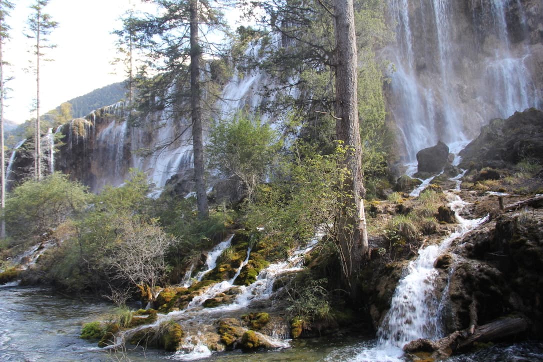 Waterfalls flowing through a forested mountain landscape